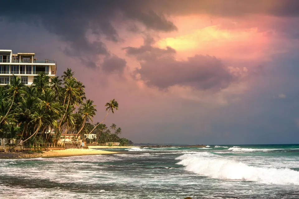 Playa con palmeras y oleaje al atardecer en la costa de Sri Lanka