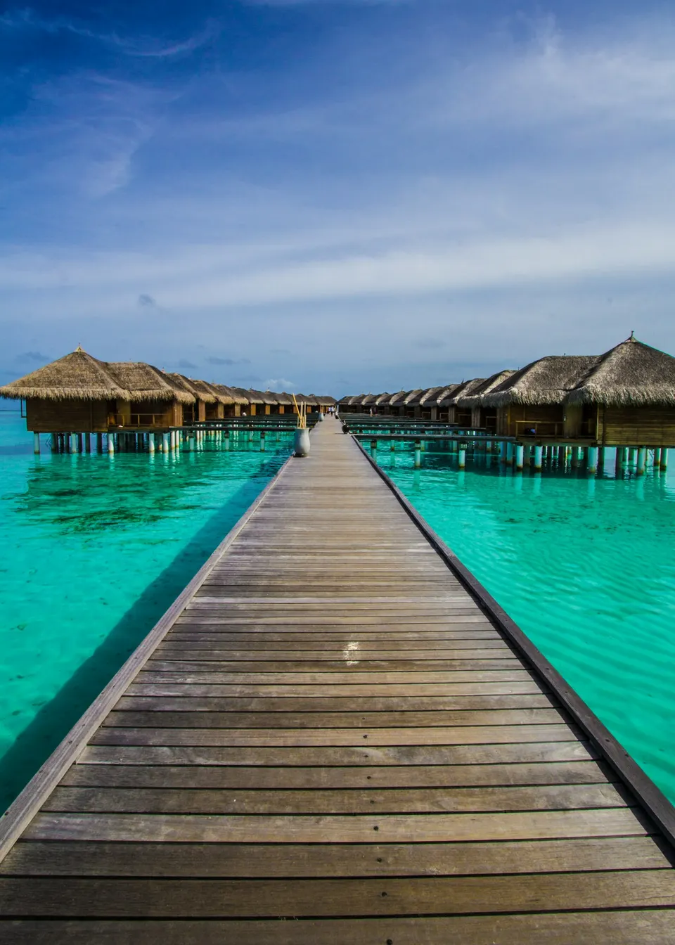 Pasarela de madera hacia bungalós sobre el agua turquesa