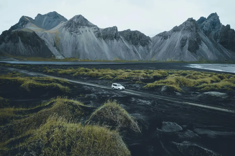 Vehículo 4x4 recorriendo un paisaje volcánico en Islandia con montañas al fondo